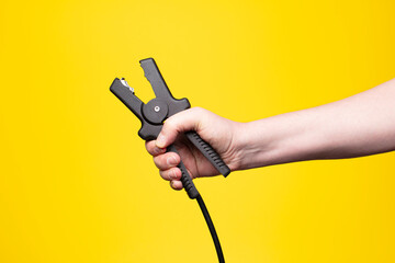 Mechanic&rsquo;s hand with jumper cable clamp &ndash; electrical energy and car maintenance concept.

