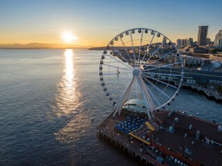 Sunset view of the Seattle Great Wheel, with people enjoying the waterfront. Iconic landmark at...
