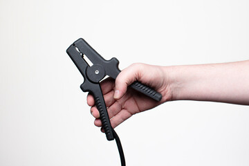 Man holding jumper cables in hand against a white studio background. Close-up shot, no face visible, with copy space. 
