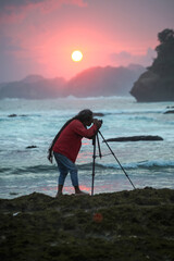 Photographer on the beach at sunset in Java Indonesia Ngliyep beach