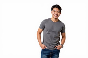 Smiling Young Asian Man in Casual Gray T-Shirt and Jeans Posing with Hands in Pockets Against a White Background, Radiating Confidence and Approachability
