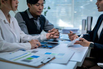 Fototapeta premium A group of people are sitting around a table with papers and a laptop