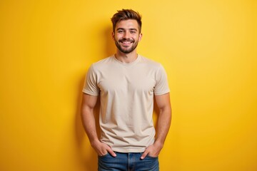 Fototapeta premium Smiling Young Caucasian Man in Casual Beige T-Shirt Posing Against Bright Yellow Background, Capturing the Essence of Happiness and Confidence in a Modern Setting