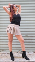 Obraz premium Fashionable woman poses in a mini skirt and boots, standing confidently in front of metal roller shutters