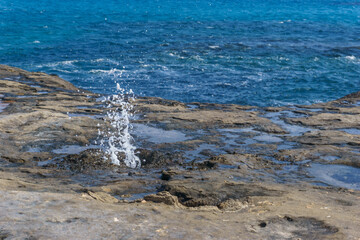 Fototapeta premium sea water splashing out of underground holes of petrified tree trunks and roots, Geopark Agios Nikolaos Petrified Forest, Laconia, Peloponnese, Greece