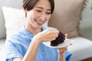 ブドウを食べる若い女性　ライフスタイルイメージ	
