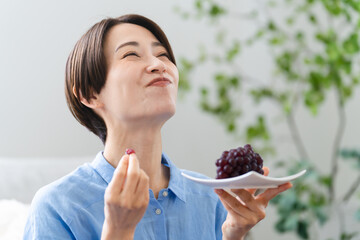 ブドウを食べる若い女性　ライフスタイルイメージ	
