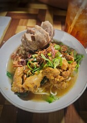 A bowl of Mie Ayam or Chicken noddles, a popular Indonesian noodle dish. Served with meatballs, seasoned chicken, often cooked in soy sauce, chopped green onions and chili sauce
