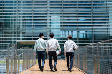 屋外を歩く作業着を着た複数のビジネスマンの後ろ姿