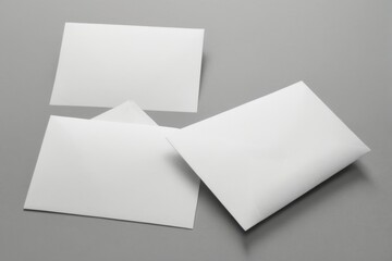 Minimalistic white cards in triangular layout on grey background, with glossy surface and neat curled edges. Clean design concept.