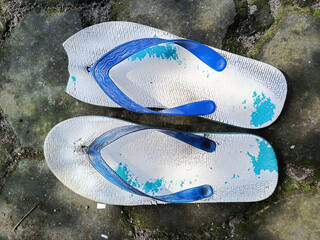 A pair of worn down blue flip flop with broken side.
