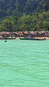 Witness the breathtaking views of Surin Island in Thailand, where turquoise waters meet picturesque huts and vibrant boats. Enjoy the peaceful ambiance and stunning nature all around.