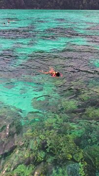 Experience the breathtaking beauty of Surin Island in Thailand. Swimmers glide through the turquoise waters, revealing stunning coral reefs and diverse marine life. A perfect tropical getaway awaits.