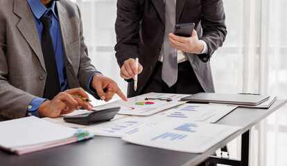 Team of confident business people point to graphs and smartphone use charts to analyze market data, balance sheet, account, net profit to plan new sales strategies to increase production capacity.
