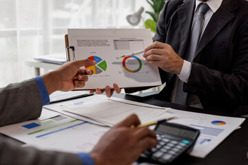 Team of confident business people point to graphs and charts to analyze market data, balance sheet, account, net profit to plan new sales strategies to increase production capacity.
