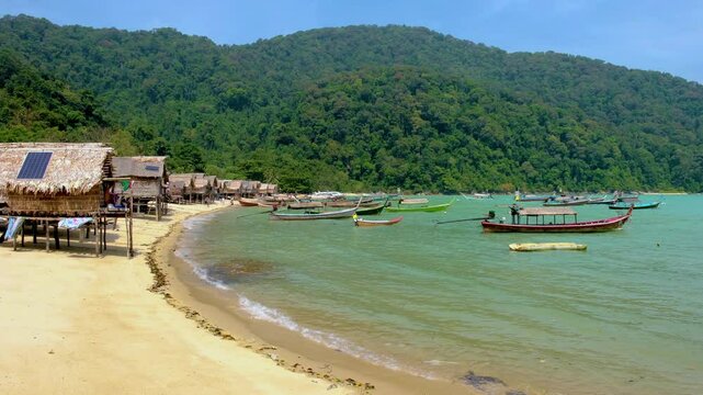 Discover the serene shores of Surin Island, Thailand, featuring crystal-clear waters and traditional fishing boats. Traditional Moken village on the beach
