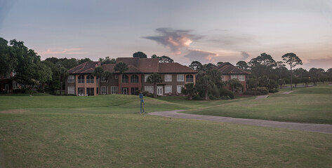 Cottage house with sloed front lawn against the sunset sky background in Destin, Florida