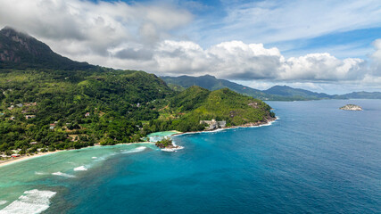 Obraz premium Coastal green hills with a turquoise ocean, small village structures, and sandy shorelines. Seychelles, Mahe.