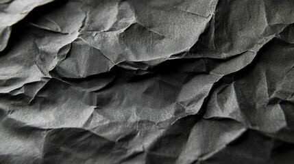 Close-up shot of dark crumpled paper texture. Ideal for backgrounds, adding depth and texture to designs, evoking a sense of drama or mystery.