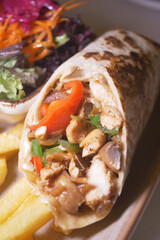 Delicious chicken burrito served with fresh salad and fries