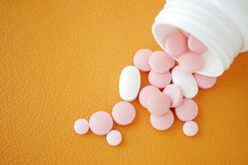 Colorful medication tablets spilled on an orange surface