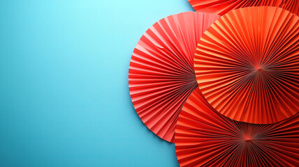 Vibrant composition of red paper fans against a soft blue background creating a playful