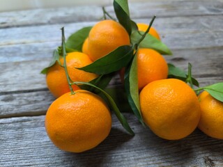 Juicy ripe tangerines with green leaves on a wooden table