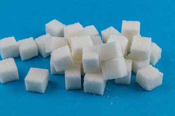 White sugar cubes scattered on a bright blue background in culinary context