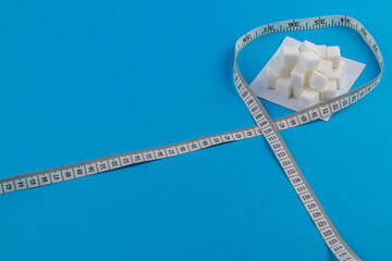 Sugar cubes on a measuring tape signify health awareness and nutrition