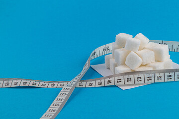 Sugar cubes with measuring tape on a blue background for kitchen use