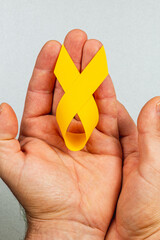 Hands holding a yellow ribbon symbolizing solidarity in cancer awareness