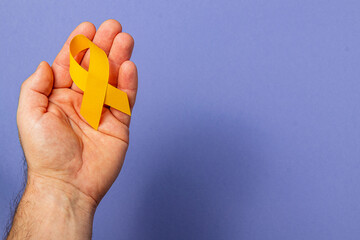 Support and awareness for cancer through a yellow ribbon in hand