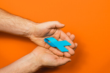 Blue ribbon for cancer awareness on an orange background