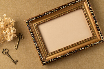 Empty frame with flowers and keys on fabric background from above. Retro style. Flat lay, top view.
