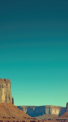 Majestic rock formation under clear blue sky with distant mountains and serene landscape