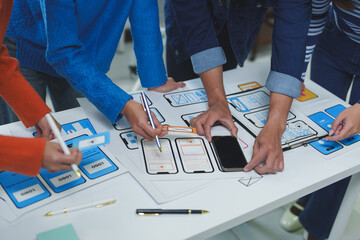 Ux designers collaborating on wireframes while analyzing a smartphone, focusing on creating an innovative mobile application that enhances user experience and interface design