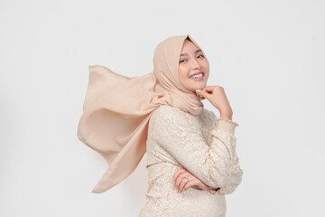 Elegant young Asian Muslim woman wearing dress with hijab waving in the wind, modelling pose.