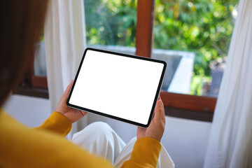 Mockup image of a woman holding tablet with blank desktop white screen at home