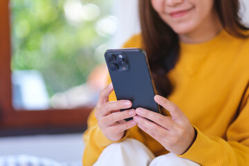 Closeup image of a woman holding and using smart phone at home