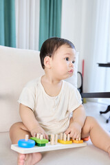 The baby is sitting on a white couch, holding a toy keyboard in his hands.