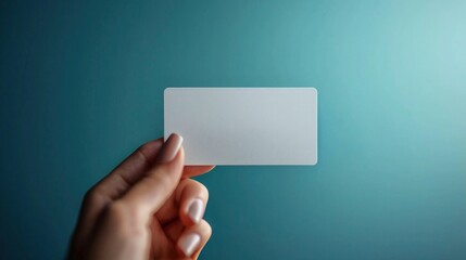 A hand holds a minimalist matte white business card mockup against a smooth blue backdrop, emphasizing empty space available for custom text and creative design opportunities