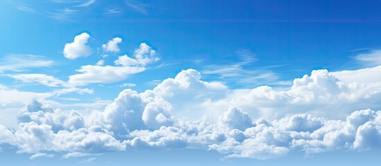Serene blue sky with soft white fluffy clouds creating a tranquil scene ideal for copy space positioned in the upper half of the image
