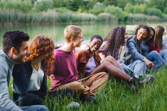 Diverse group of friends laughing together by the lake in nature