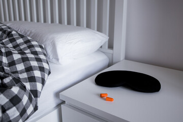 Cozy bedroom with sleep mask, earplugs, and checkered bedding for a restful night