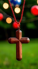 Wooden Christian Cross Pendant on Red Cord with Festive Bokeh Lights Decoration Celebration