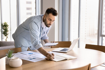 Focused man multitasking, working on analytical task, prepare presentation or conducting research...