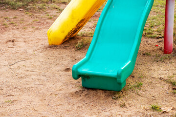 A blue slide in sandy area, shaded by a tree in the background