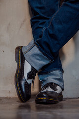 Close up of a man's legs wearing blue jeans paired with two-tone black and white genuine leather...