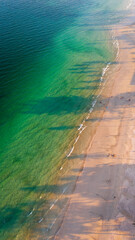 Aerial Vertical Blue ocean water with palm tree shadow
