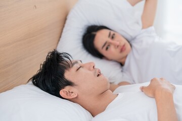 Couple in bed during morning hours, one partner sleeping while the other looks concerned